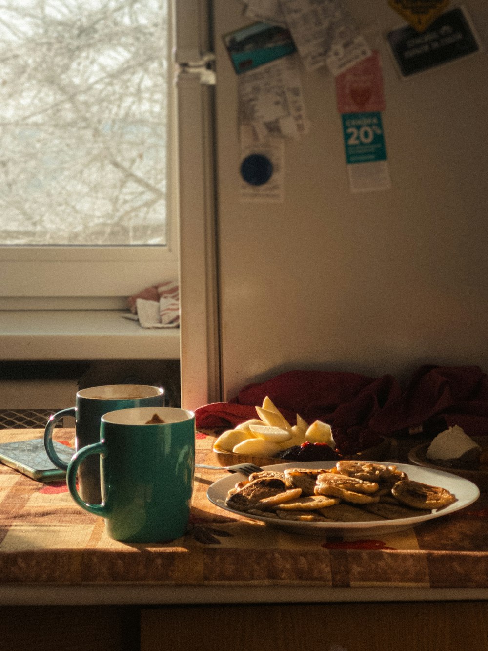 green ceramic mug beside brown ceramic plate on table