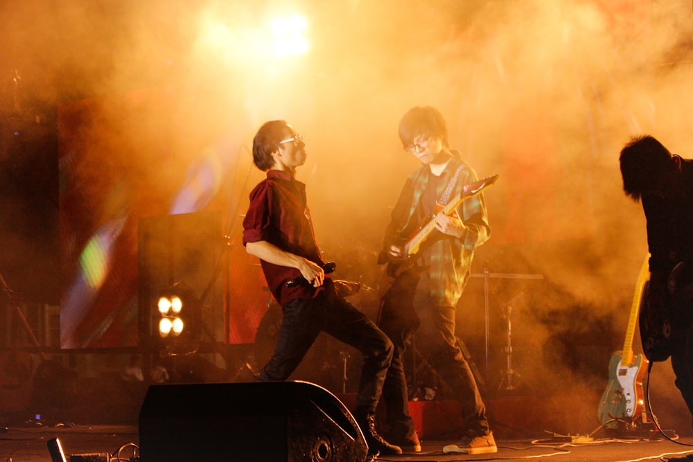 man in black jacket playing guitar on stage