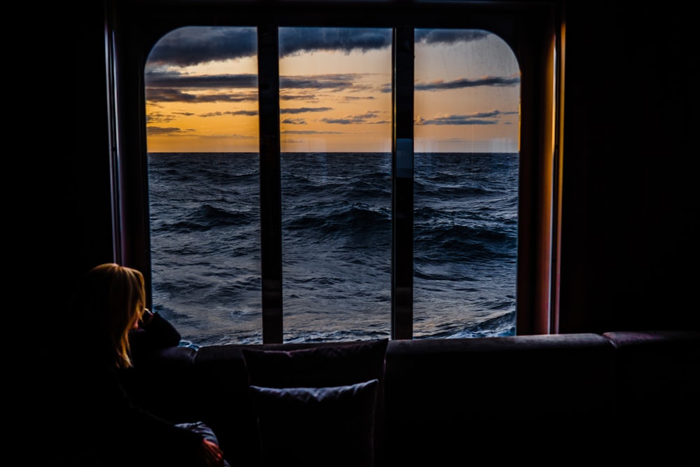 夕暮れ時に海を眺めるソファに座る女性