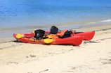 red kayak on white sand beach during daytime