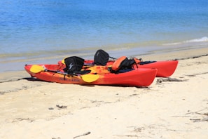 red kayak on white sand beach during daytime