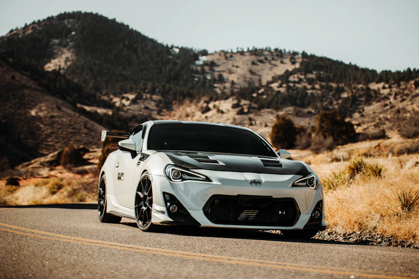 A sleek black Lamborghini Aventador parked on a sunlit coastal road, highlighting its sharp lines and luxury appeal.