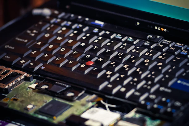 Close-up of hands replacing a laptop keyboard with precision tools.