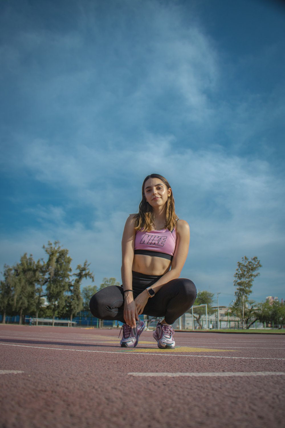 woman in pink tank top and black shorts sitting on basketball court during daytime