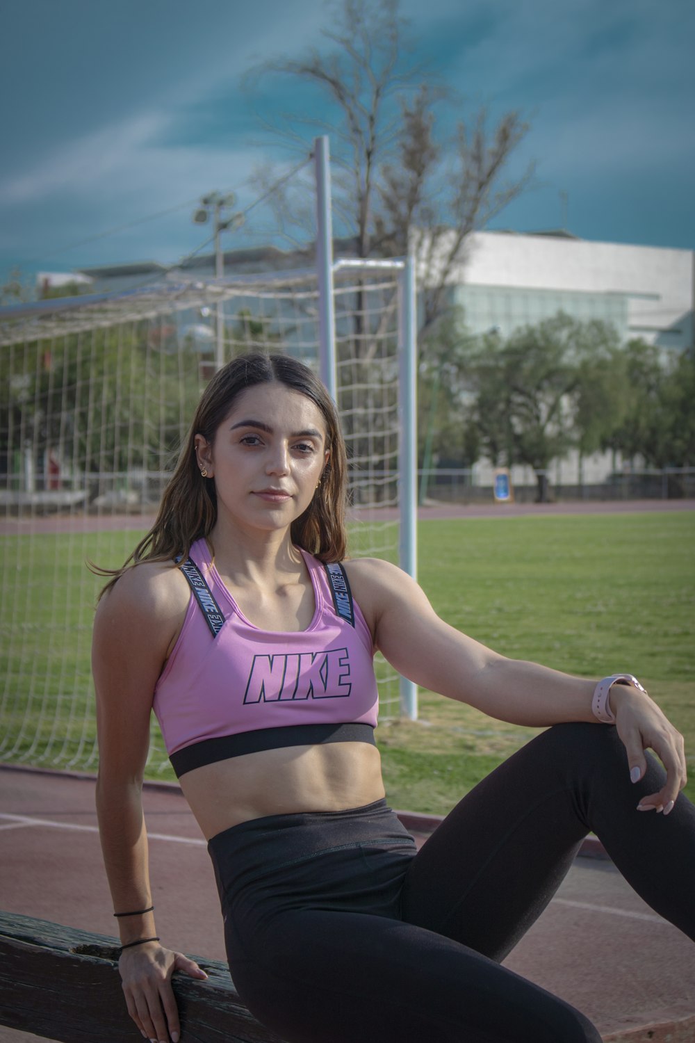 woman in pink sports bra and black leggings sitting on brown field during daytime
