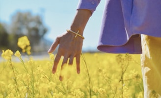 person in brown long sleeve shirt standing on yellow flower field during daytime