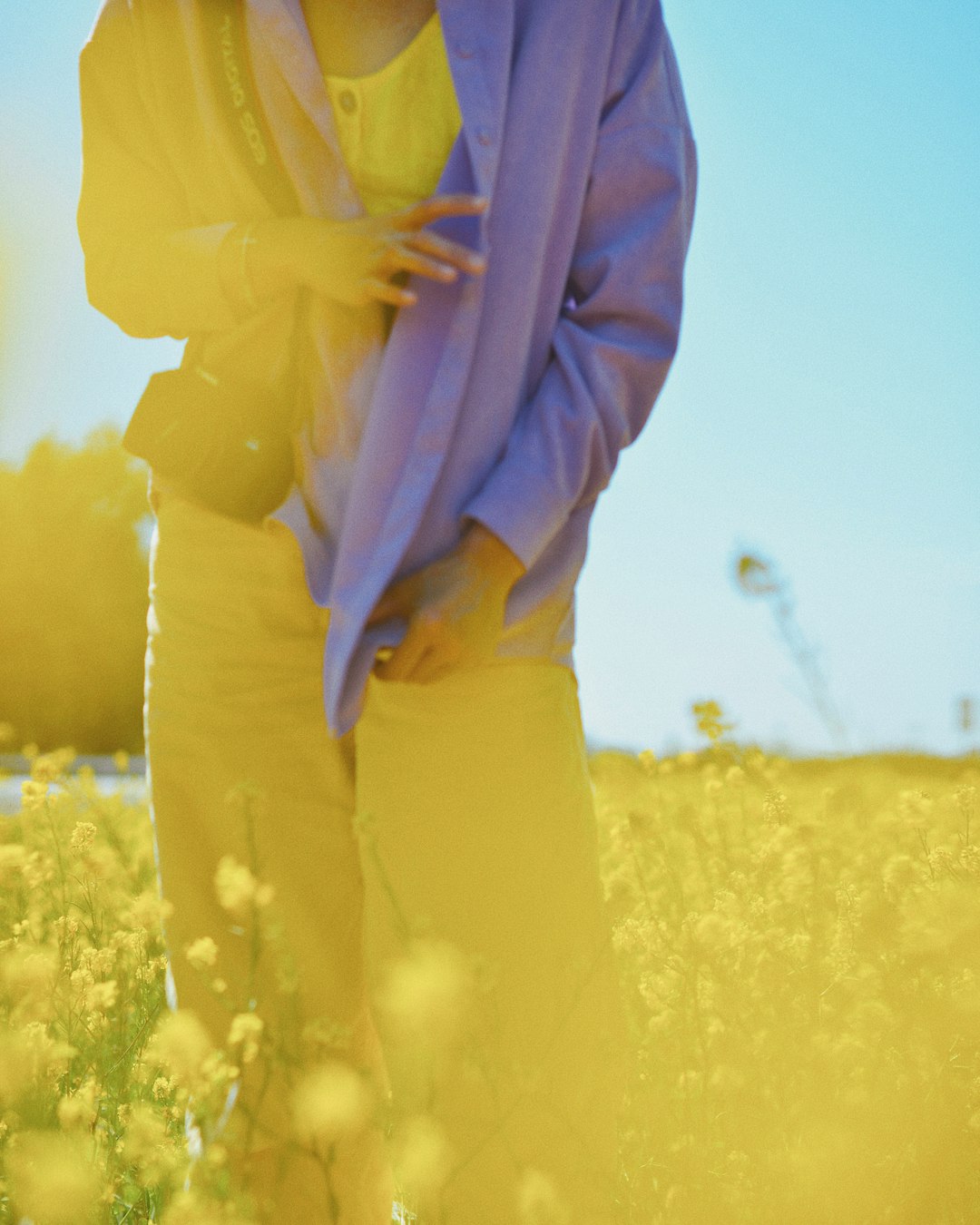 person in yellow long sleeve shirt and yellow pants standing on yellow flower field during daytime
