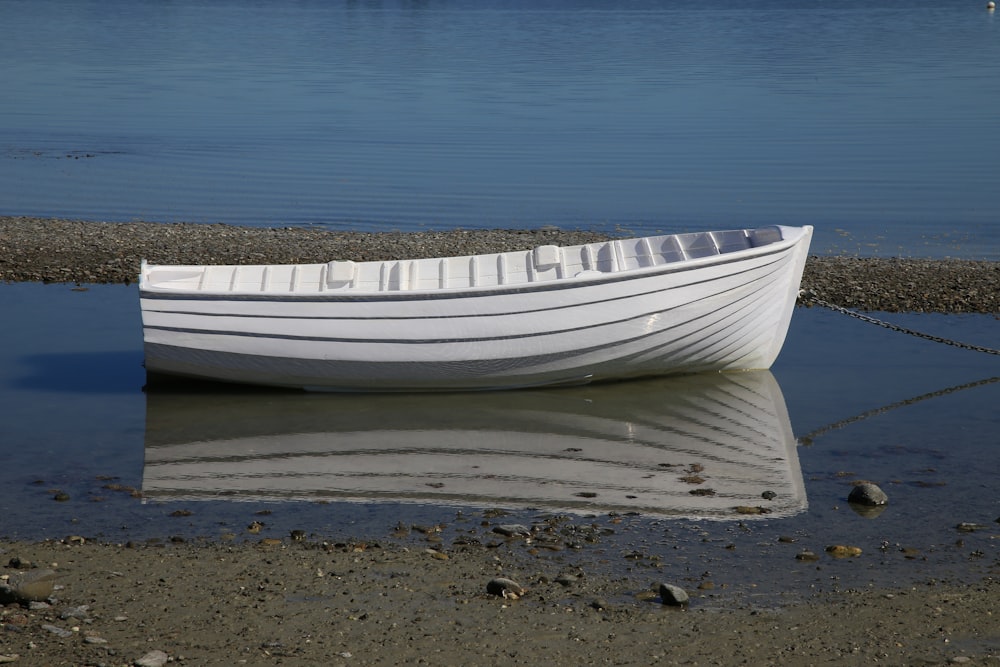 昼間の灰色の砂浜に浮かぶ白いボート