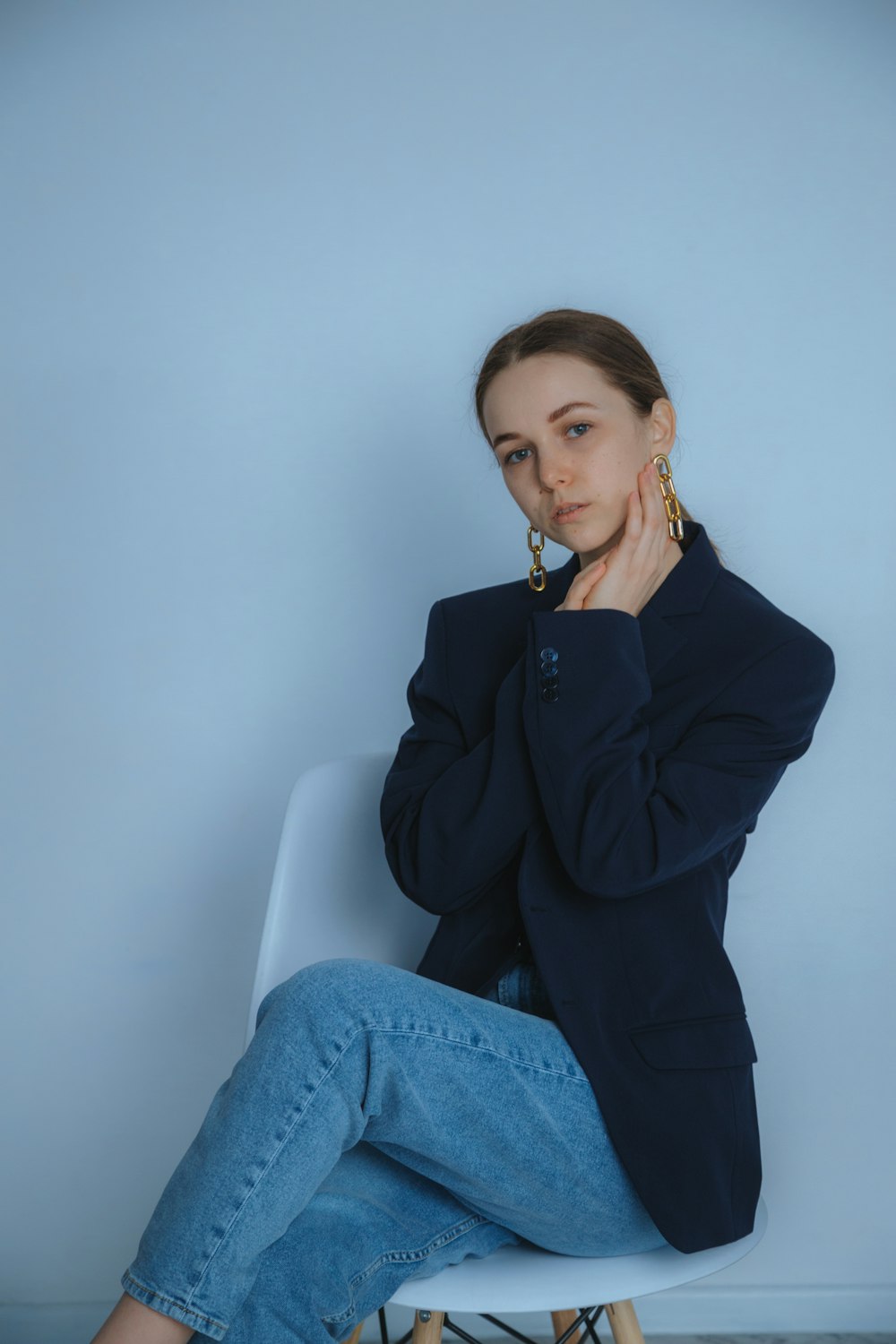 woman in black blazer and blue denim jeans sitting on white chair photo –  Free Russia Image on Unsplash