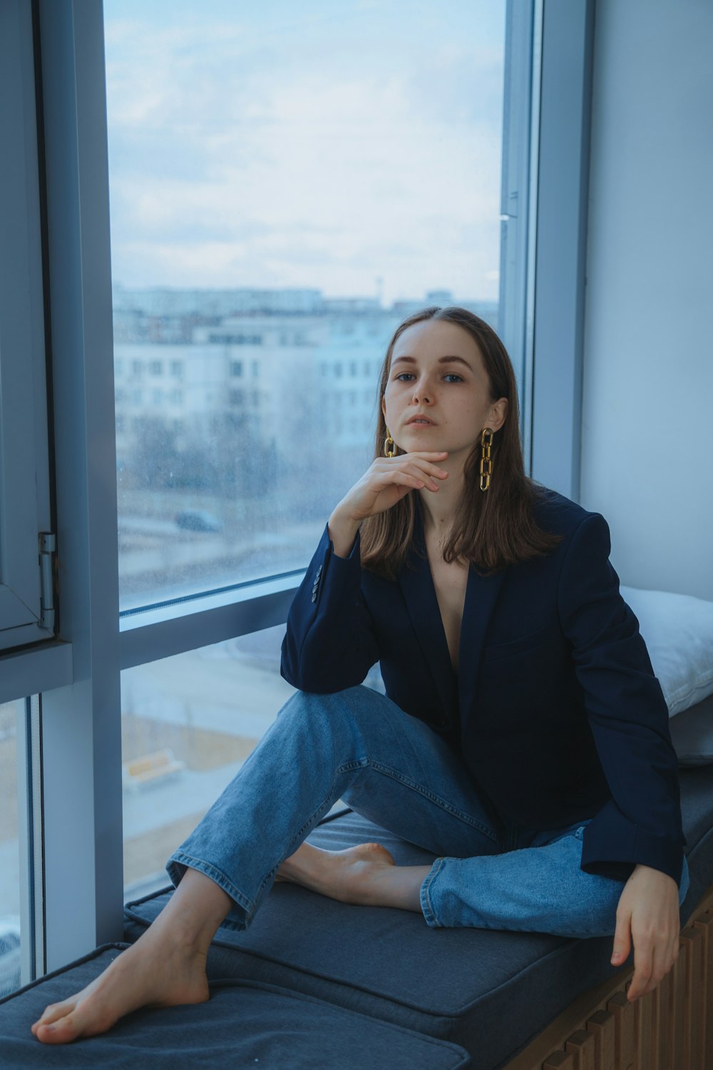 woman in black blazer and blue denim jeans sitting on window