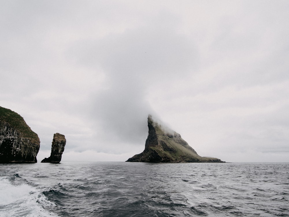 brown rock formation on sea under white clouds during daytime