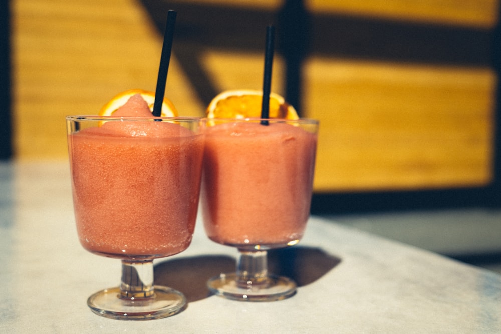 two clear drinking glasses with orange juice