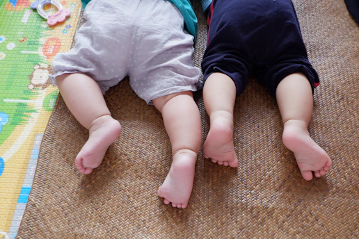 baby in white shirt and black pants lying on brown carpet