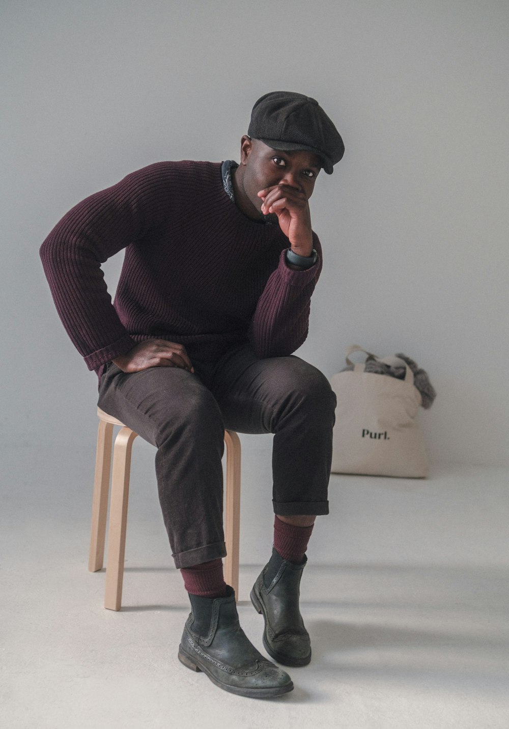 man in red sweater and black pants sitting on brown wooden chair