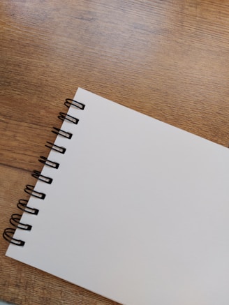 Close-up of a spiral-bound notebook made with recycled paper, resting on a wooden desk.