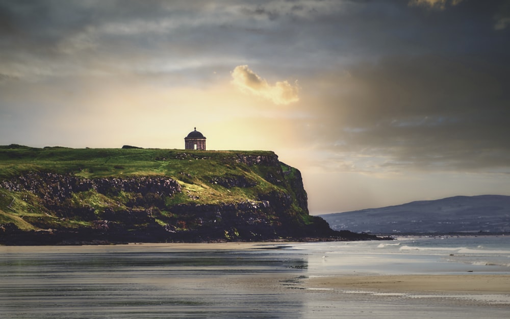 Silhouette de phare sur une colline près d’un plan d’eau pendant la journée