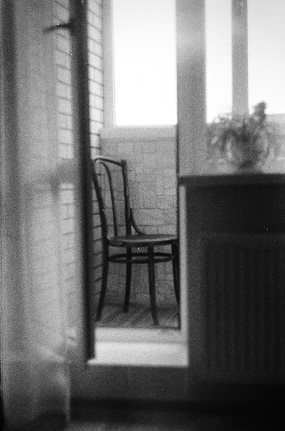 grayscale photo of chair near window