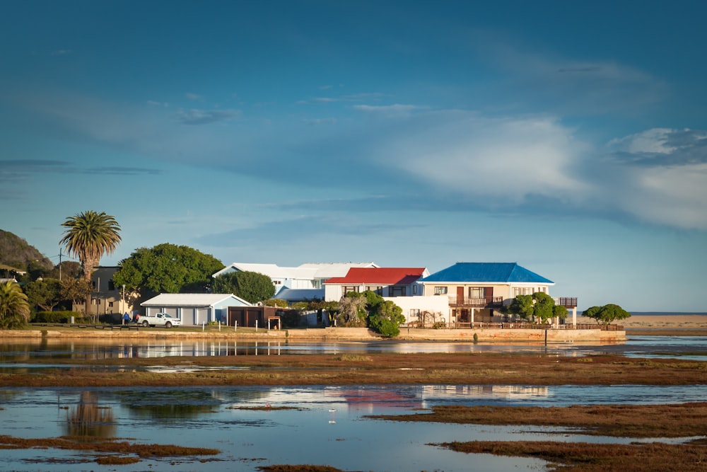 white and blue house near body of water under blue sky during daytime