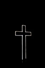 Soft glowing cross and open Bible illuminated against a pitch-black background.