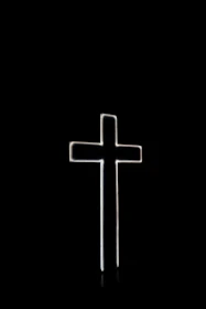 Soft glowing cross and open Bible illuminated against a pitch-black background.