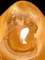 Close-up of a candle flame casting soft shadows on a textured wall.