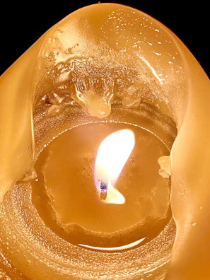 A close-up of a flickering candle flame casting warm shadows in a dim room.