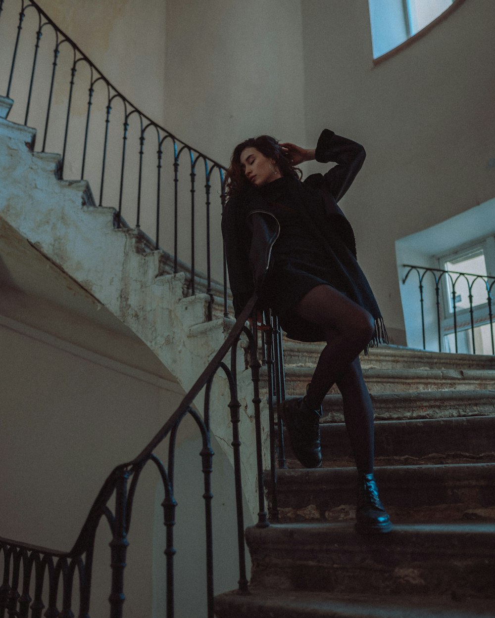 a woman in a black dress is sitting on a stair case