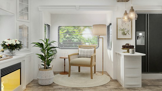 A cozy, well-lit living room area with a natural and minimalist aesthetic. There is a wooden armchair with a cushion placed on a circular rug in the center. A tall floor lamp is positioned behind the chair. Adjacent to the chair, a potted plant stands to the left, and a small wooden side table is on the right. The background features a window with blinds, through which blurred greenery is visible outside. On the left, there is a white fireplace with a yellow glow and a bouquet of flowers on the mantel. On the right, there is a kitchen counter with a cake and a coffee mug, and a black refrigerator with a water dispenser. Hanging pendant lights add a warm, welcoming glow to the room.