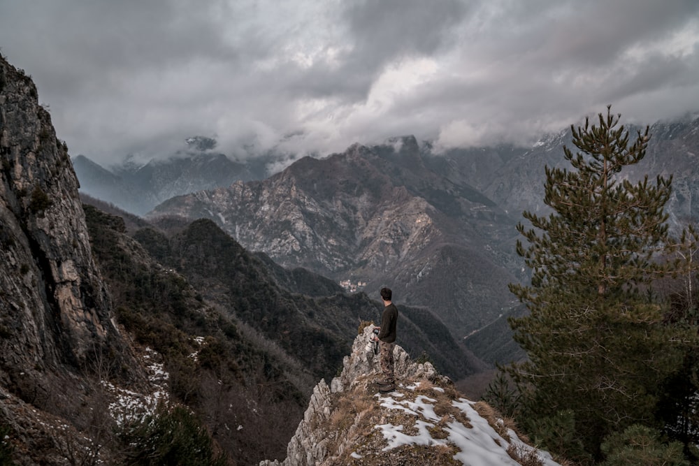 person in black jacket standing on rocky mountain during daytime