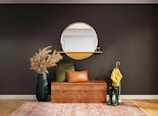 brown wooden framed brown padded armchair beside blue and white round mirror