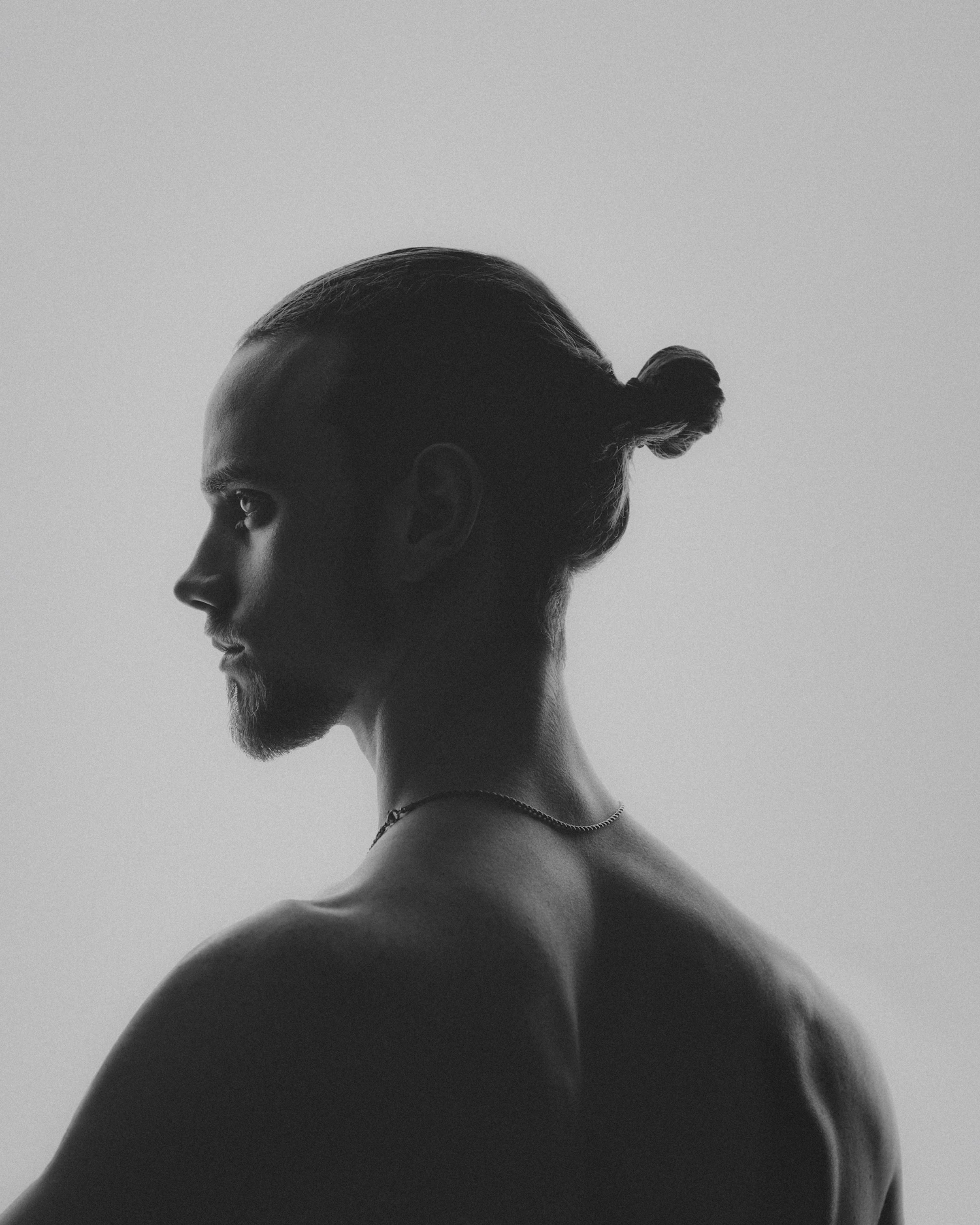 A sitter photographed in profile against a pale seamless backdrop