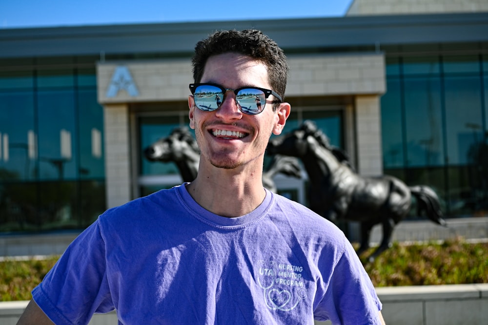 Homme en chemise bleue à col rond portant des lunettes de soleil noires