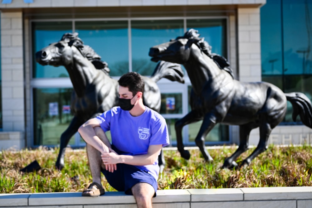 man in blue crew neck t-shirt and blue shorts sitting on black concrete bench during