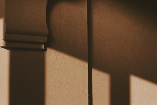 Abstract shadows cast on a textured wall in natural light.