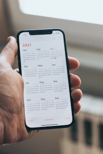 Hands holding a smartphone displaying a calendar app, representing easy online appointment booking.