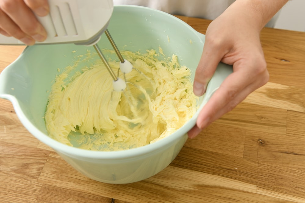 Person mit weißer Keramikschale mit gelber Suppe