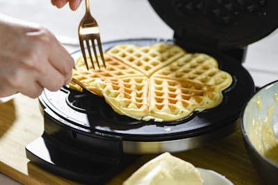 Fresh batter being poured onto a waffle iron, steam rising gently.