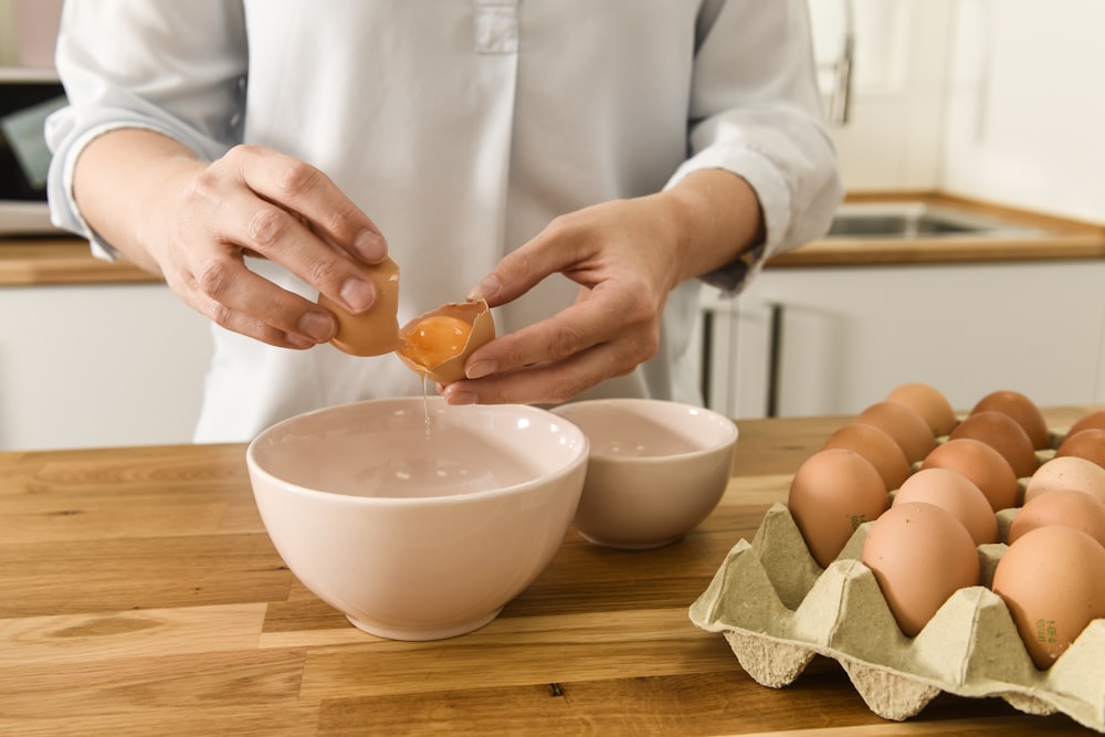 person holding orange fruit on white ceramic bowl