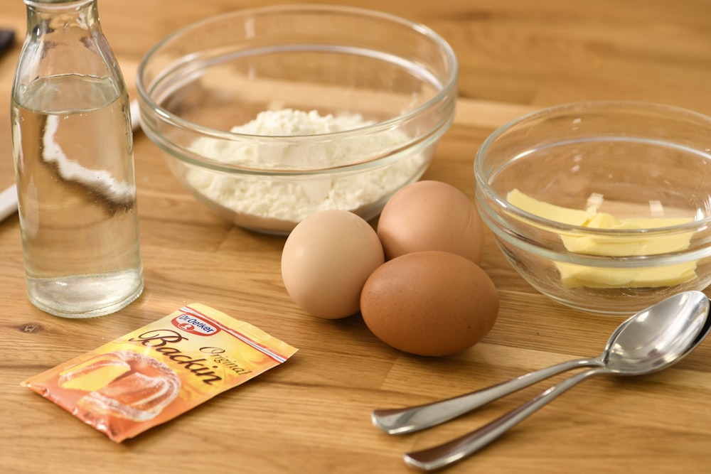 brown eggs on clear glass bowl beside stainless steel fork