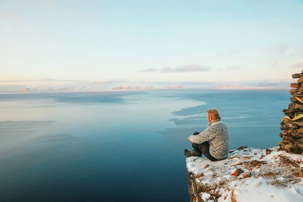 A walker resting on a rock above the fjord — Svalbard, Norway