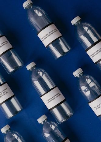 Several empty plastic bottles with labels are arranged diagonally on a deep blue background. The labels on the bottles contain text related to the environmental impact of plastic pollution.