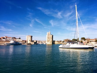 white and blue boat on water near brown concrete building under blue sky during daytime