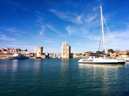 white and blue boat on water near brown concrete building under blue sky during daytime