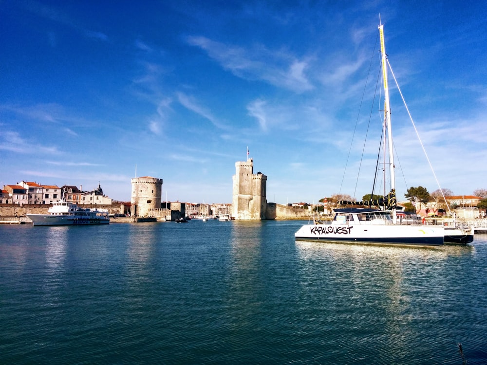 white and blue boat on water near brown concrete building under blue sky during daytime