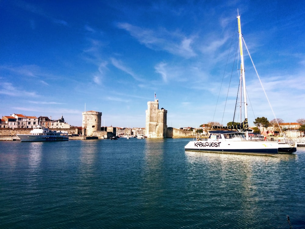 barco branco e azul na água perto do edifício de concreto marrom sob o céu azul durante o dia