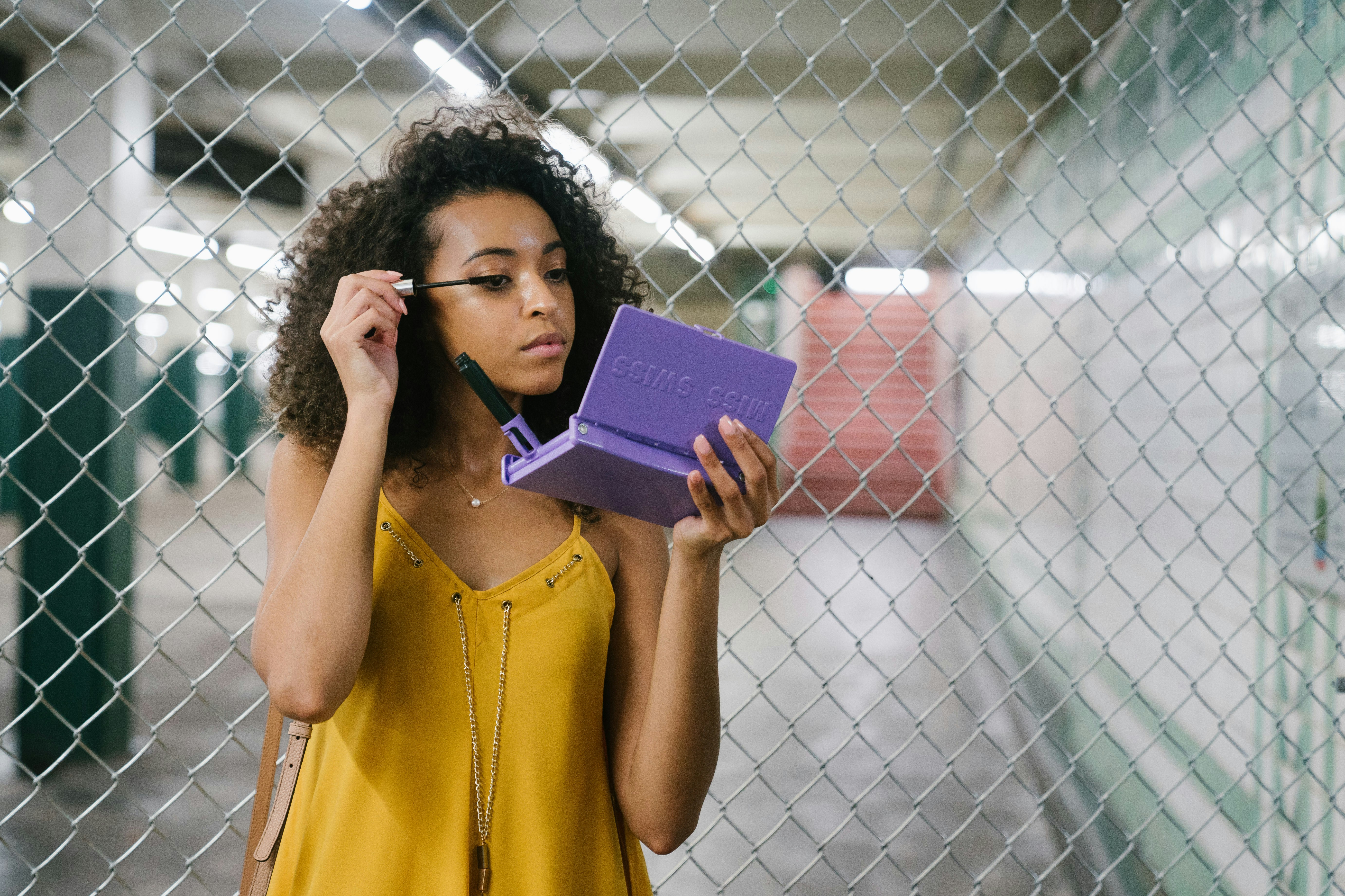 woman in yellow sleeveless dress holding purple book, MISS SWISS helps makeup wearers with glamour on the go no matter where their travels take them. The MISS SWISS makeup case was created from a personal purse catastrophe. It helps you apply your makeup easily on the go, prevents your makeup from spilling, and to prevent your makeup from getting lost. It is the perfect something blue for your wedding day. Touching up your makeup after your ceremony or between photos is a breeze.