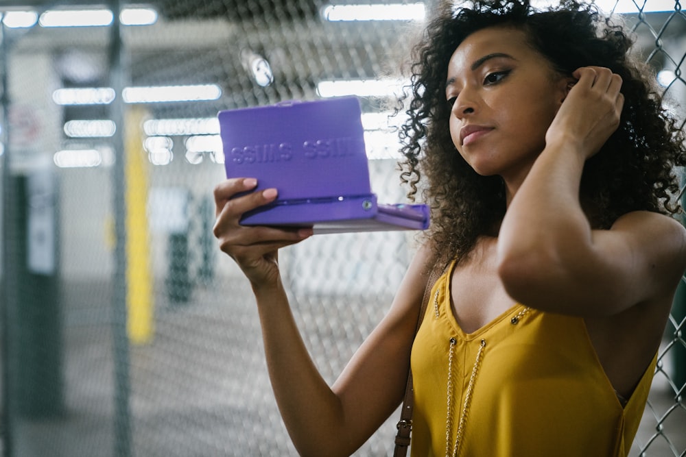 紫色のタブレットコンピュータを持つ黄色いタンクトップの女性