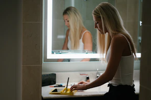woman in white tank top standing in front of mirror