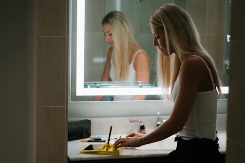 woman in white tank top standing in front of mirror