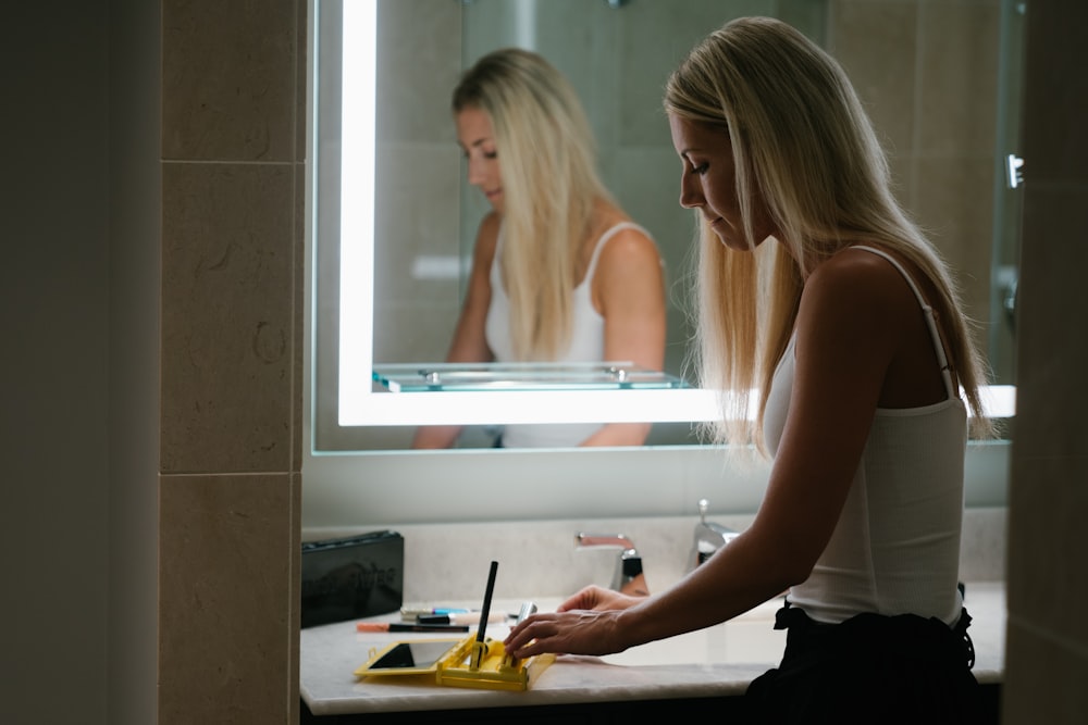 woman in white tank top standing in front of mirror